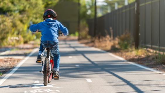 Photo of a child riding a bike on a bike trail.